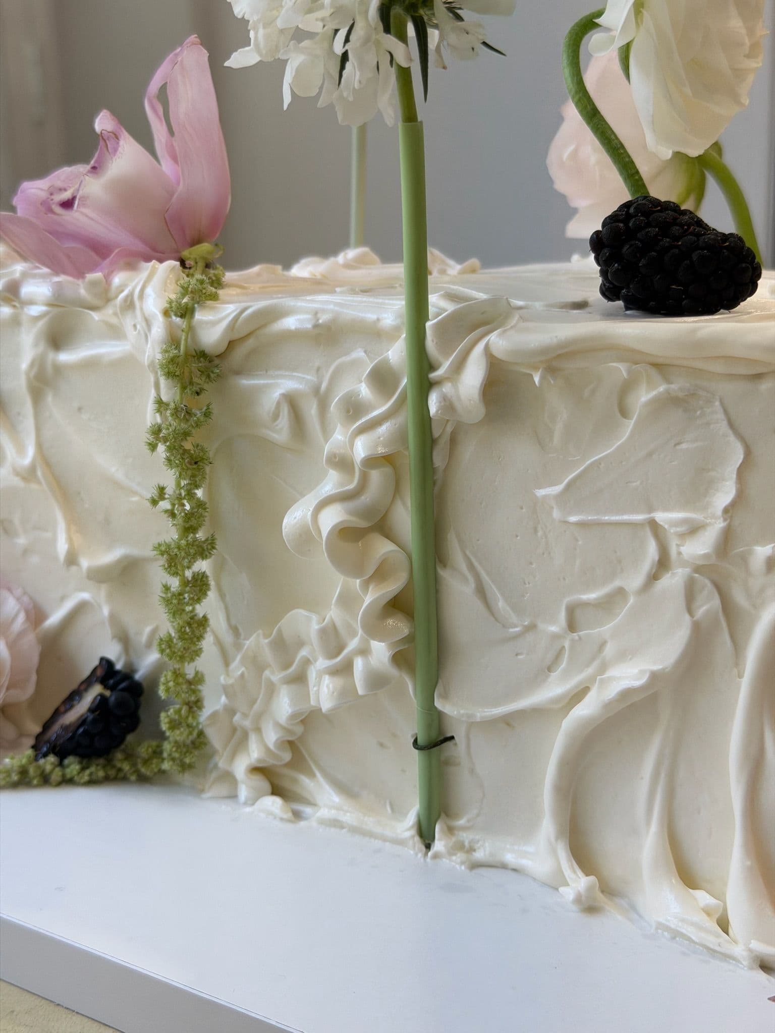 Close study of ruffled buttercream with a pink cymbidium orchid, blackberry and trailing amaranthus