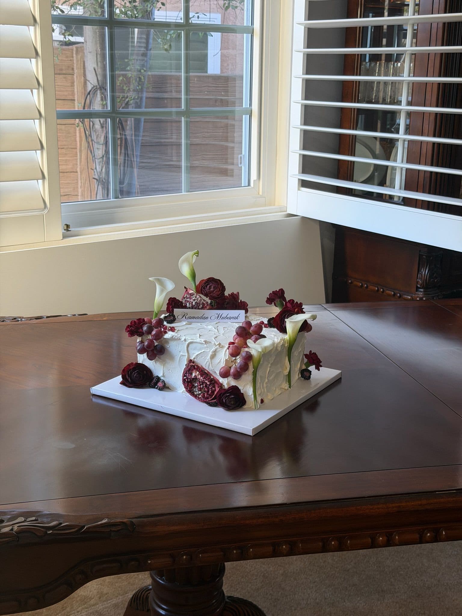 Textured sheet cake with crimson florals and calla lilies on a dining table