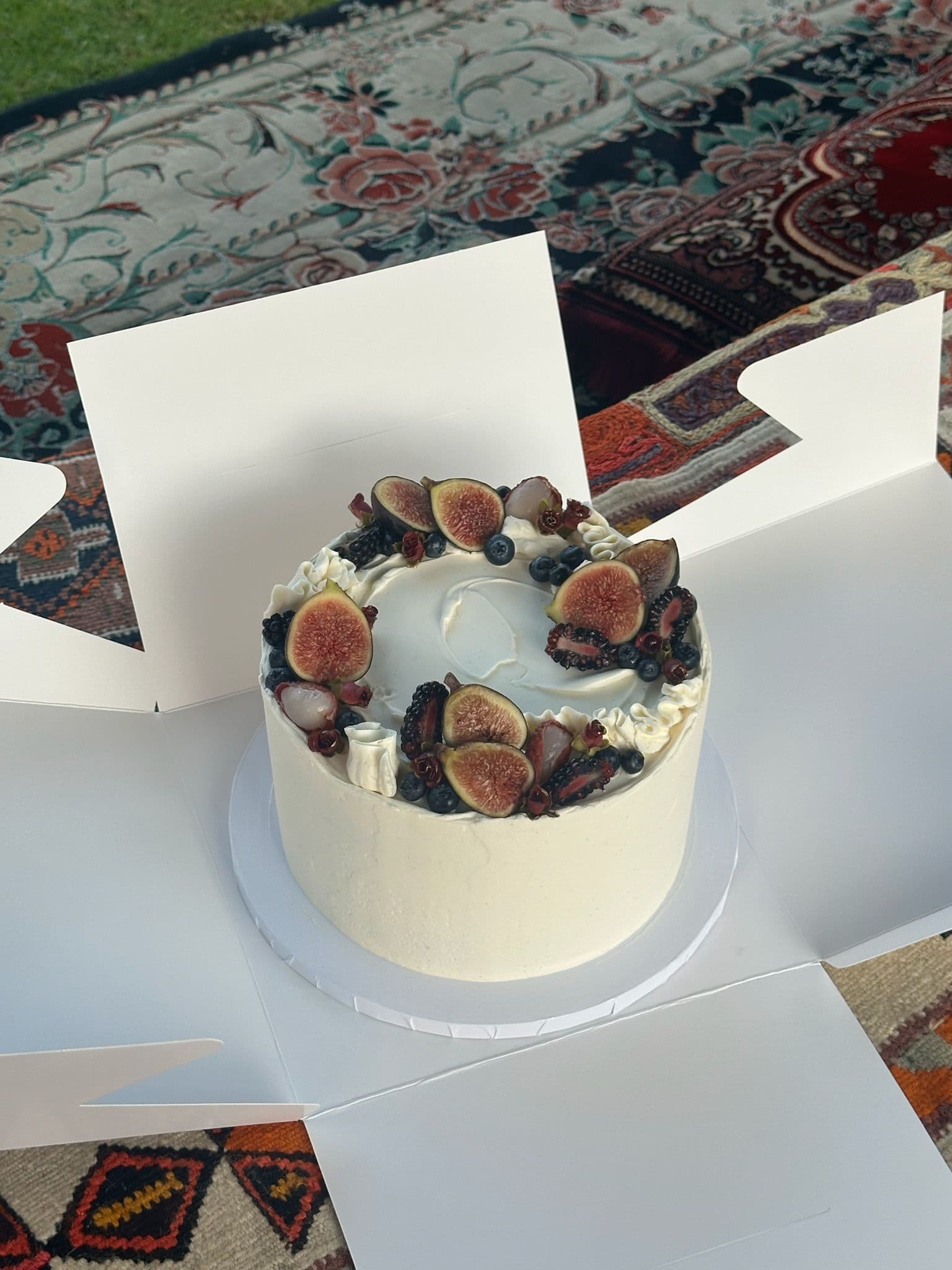 Fig and berry cake with textured buttercream, opened on a patterned rug
