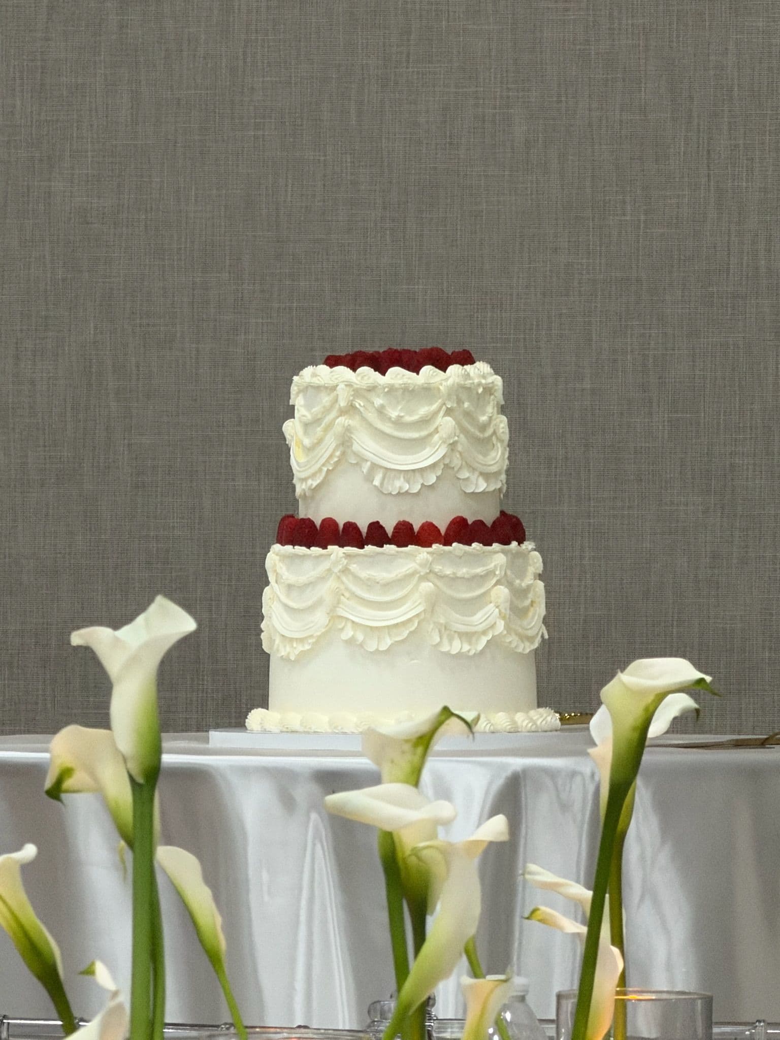 Two-tier vintage piped cake with raspberries, styled with white calla lilies
