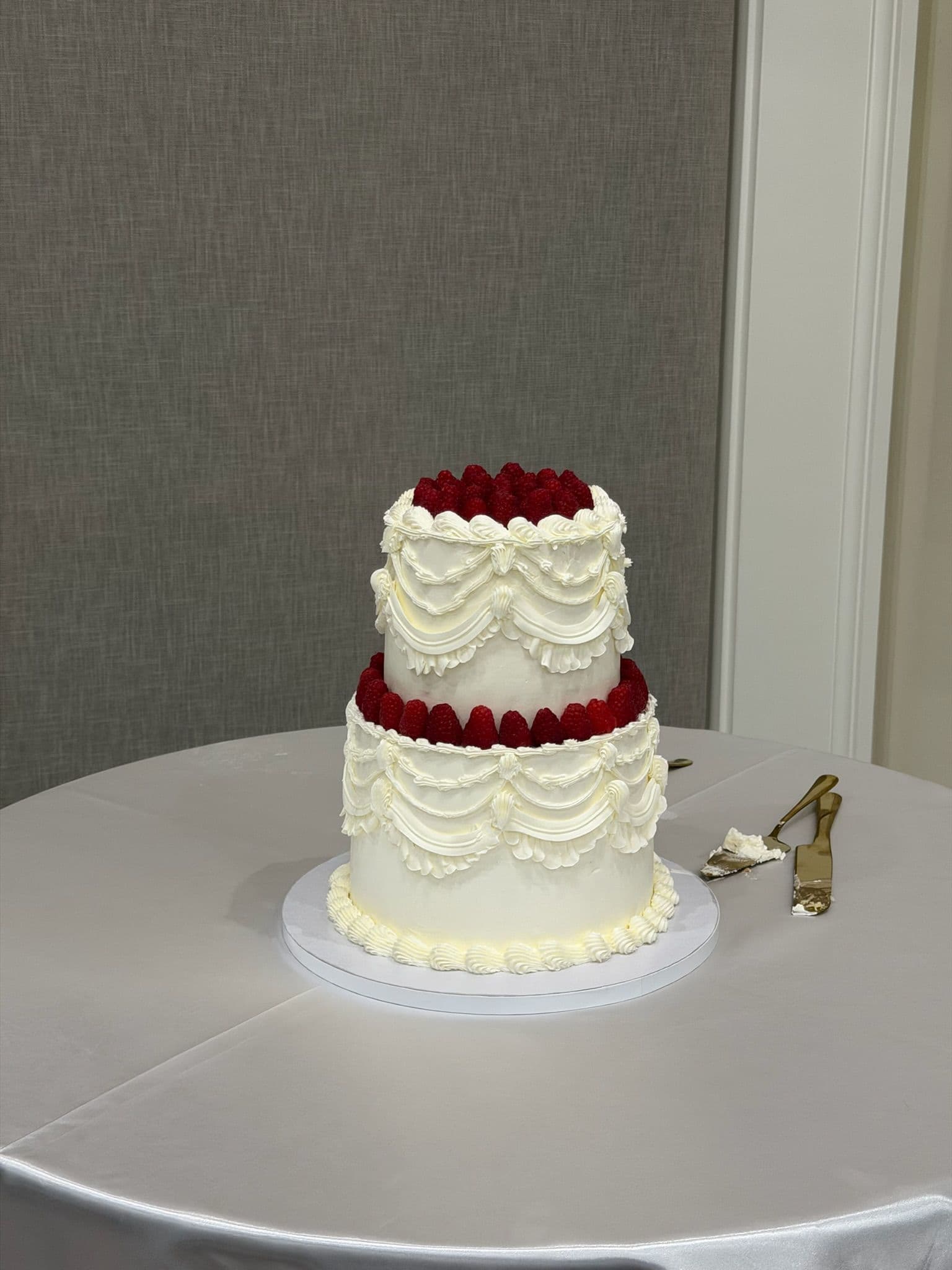 Two-tier cake with vintage piped buttercream swags and a crown of fresh raspberries